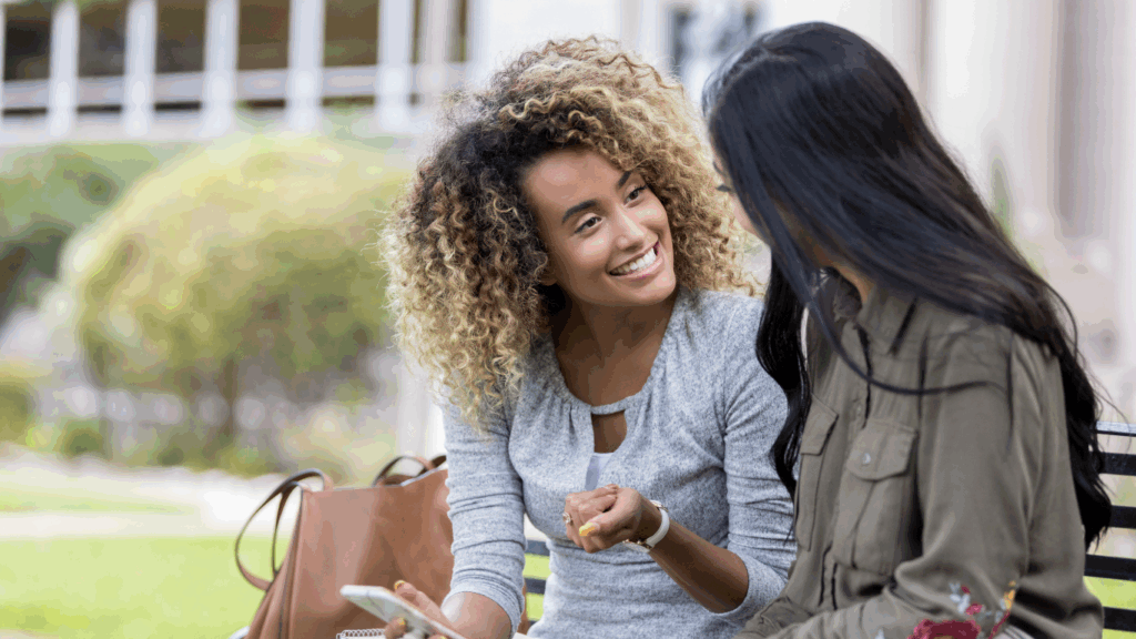 Two frinds chatting while holding a phone.